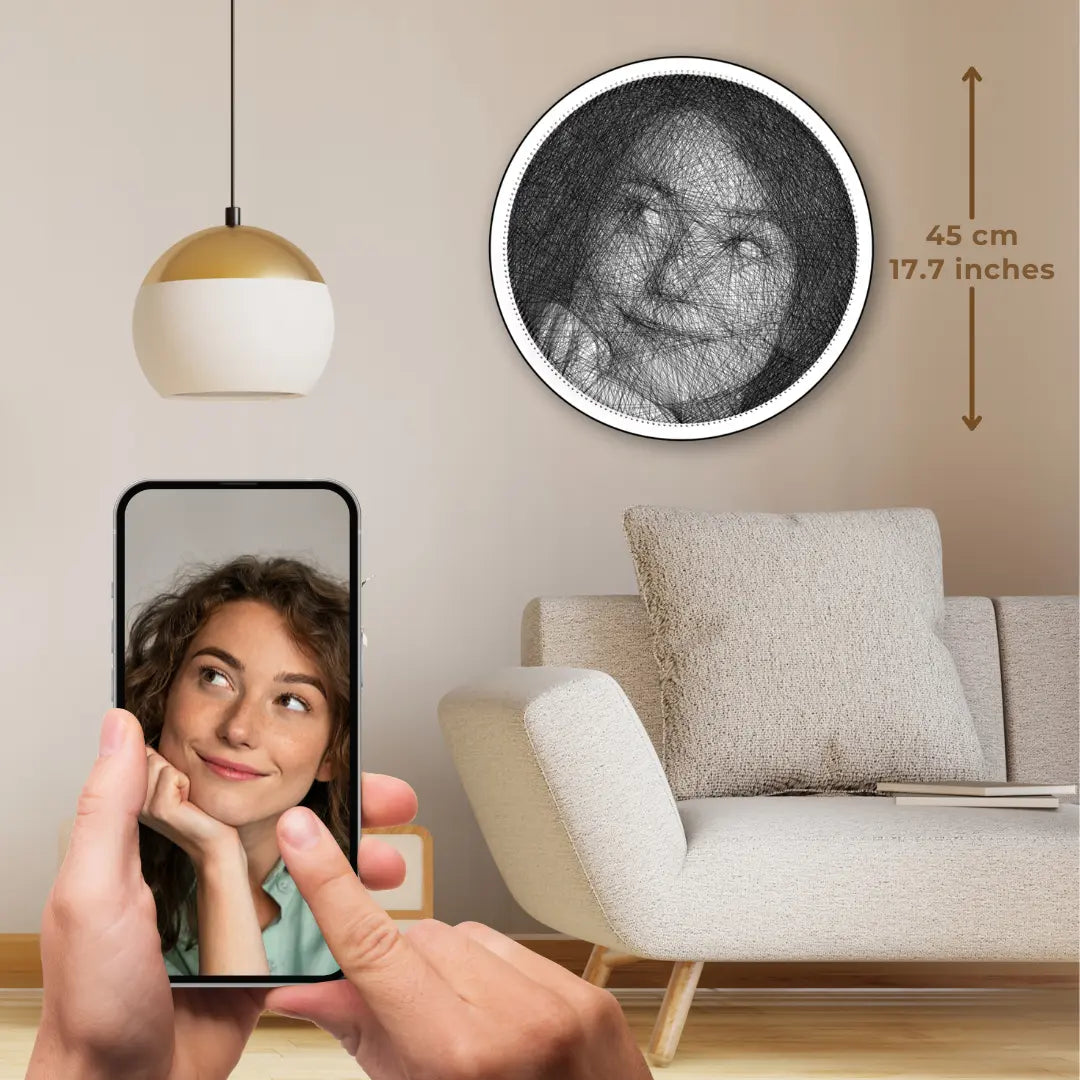 Custom black string art of a girl’s selfie on white board with black string, original image shown on a phone held in hand