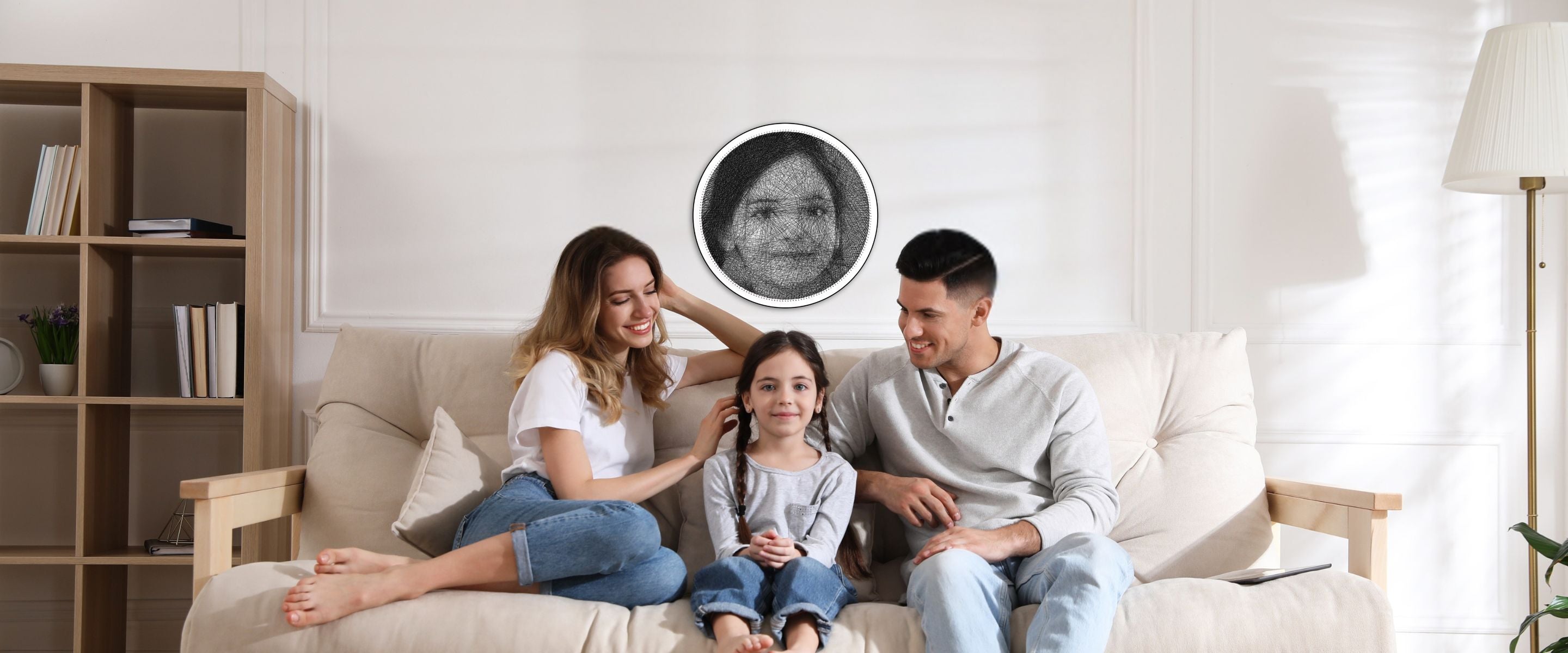 A couple sitting on either side of their daughter, with a String Art portrait of the daughter hanging on the wall behind them.