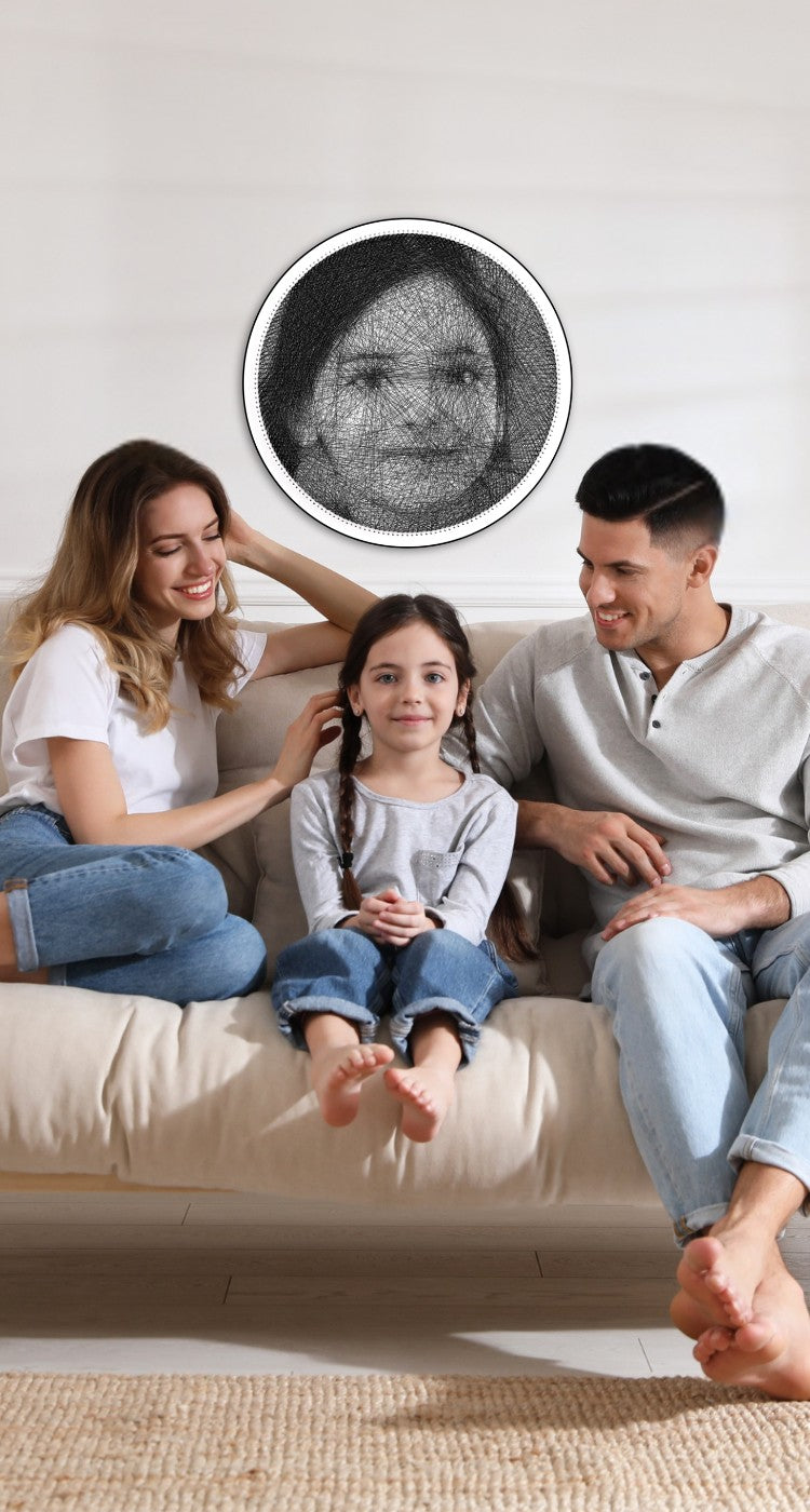 A couple sitting on either side of their daughter, with a String Art portrait of the daughter hanging on the wall behind them.