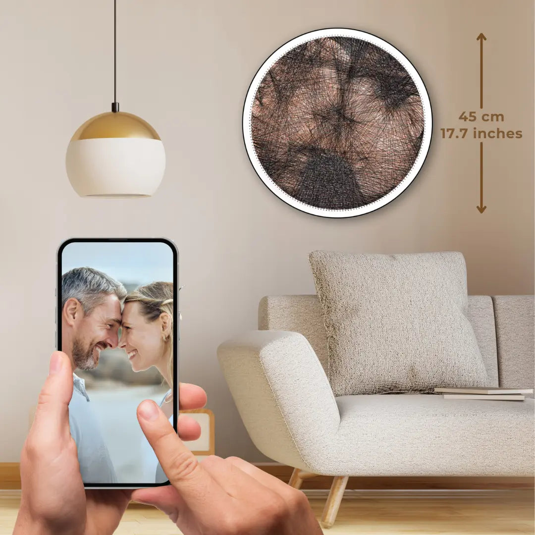 Custom color string art of a face-to-face couple on white board with color strings, original image shown on a phone held in hand