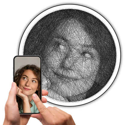 Custom black string art of a girl’s selfie on white board with black string, original image shown on a phone held in hand