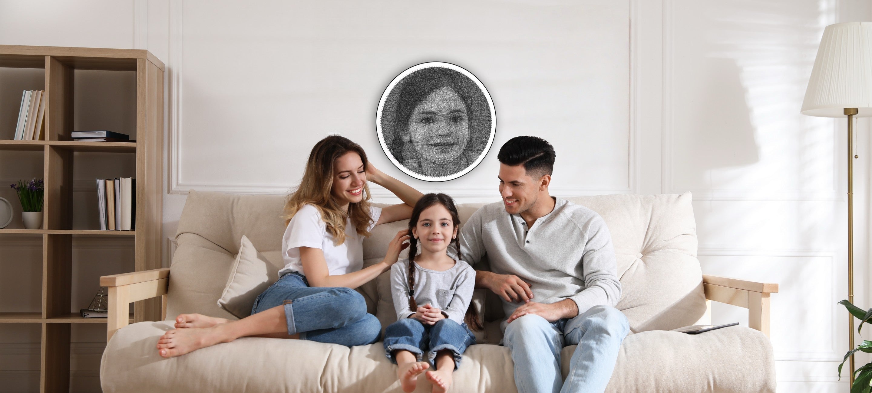 A couple sitting on either side of their daughter, with a String Art portrait of the daughter hanging on the wall behind them.